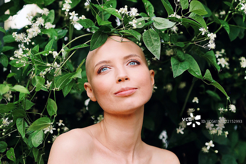 患有癌症或脱发的年轻女孩在花丛中特写肖像图片素材