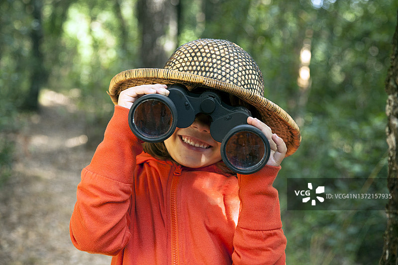 用双筒望远镜探索的快乐小女孩图片素材