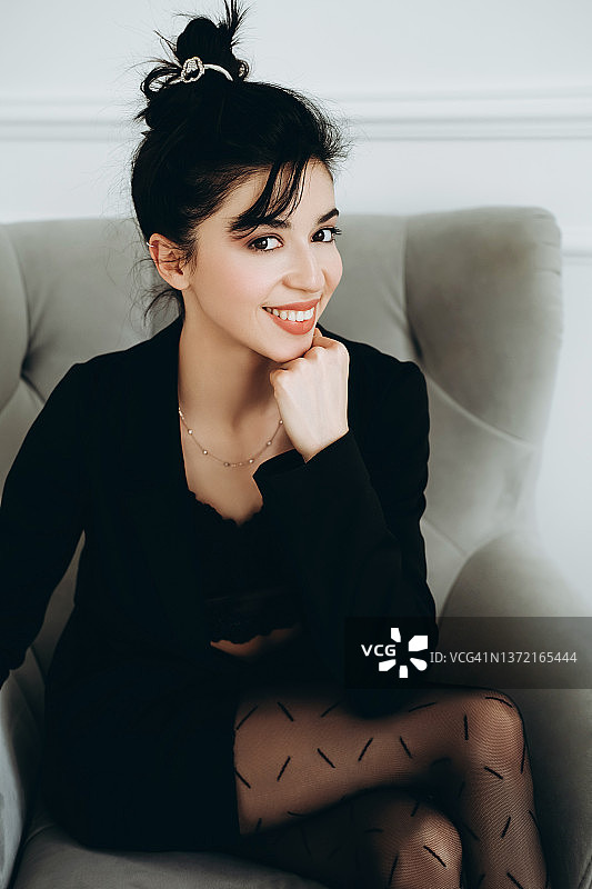 年轻女人双腿在膝盖处交叉，用拳头撑着下巴图片素材