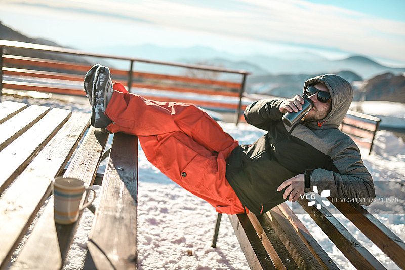 男人享受山区雪景和咖啡时光图片素材