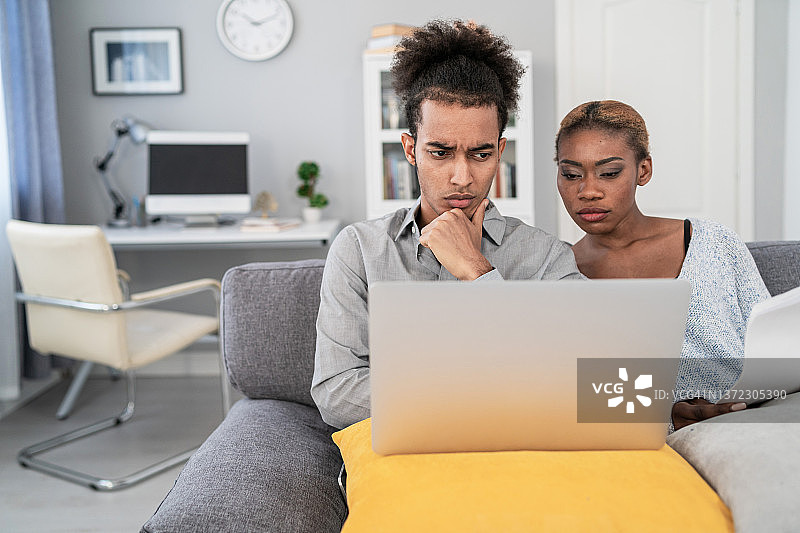 坐在沙发上制定预算的年轻非裔夫妇图片素材