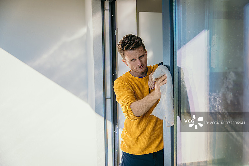 男人用抹布擦拭窗框图片素材