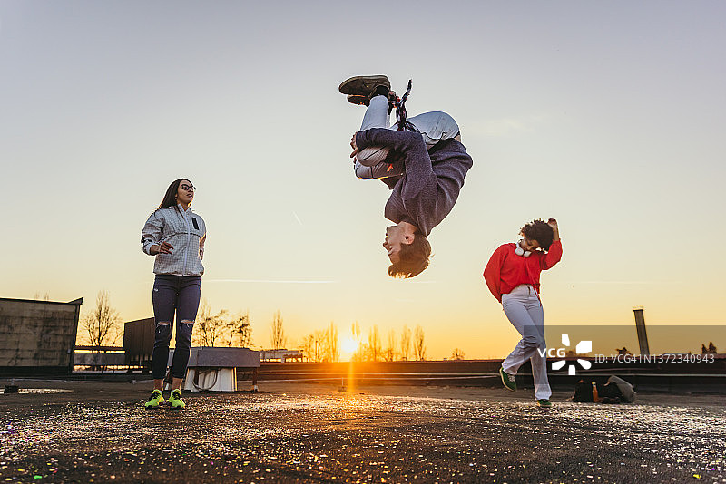 年轻男人做后空翻，背景是跳舞的女人图片素材
