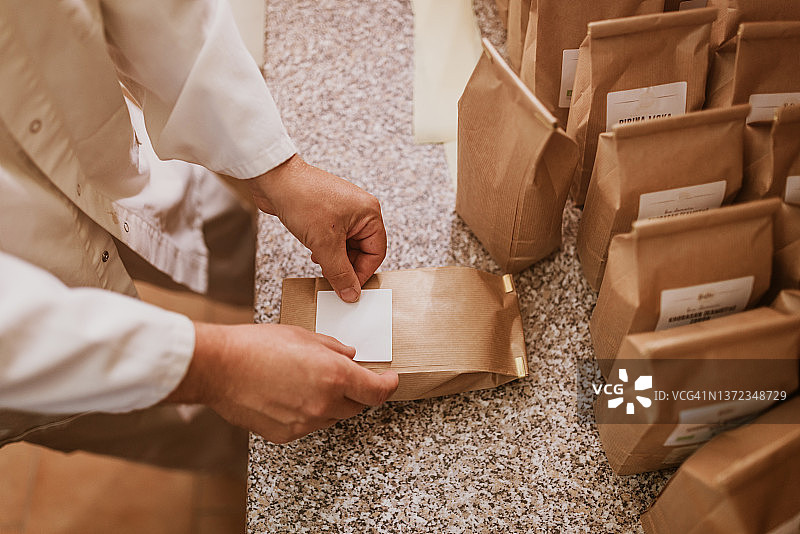 工厂里往纸袋上贴标签的男人图片素材