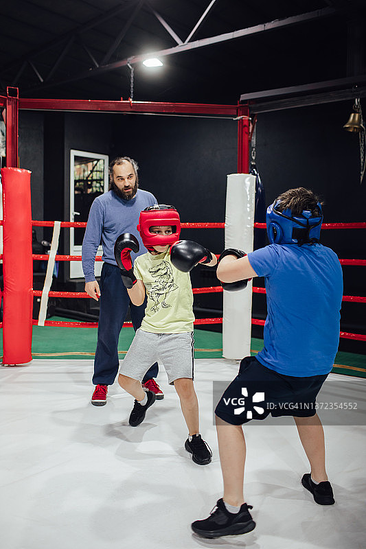 一位亚美尼亚男子在拳击台上训练他的学生，一群正在练习拳击的小男孩图片素材