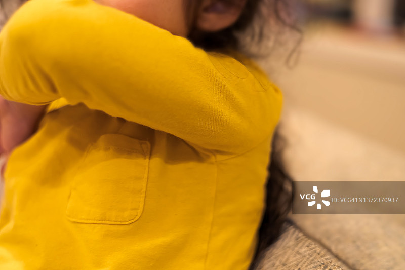 对着手肘打喷嚏或咳嗽的年轻混血女孩图片素材