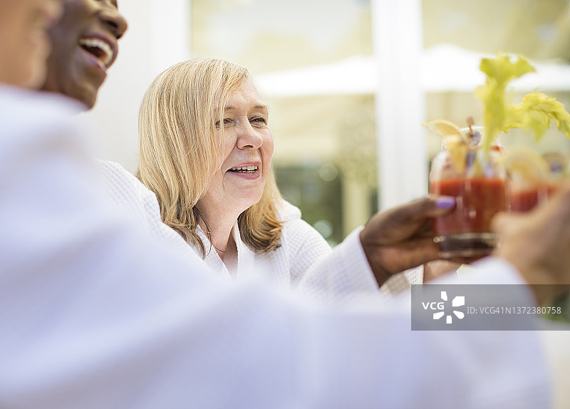 快乐的老年妇女和朋友一起享用血腥玛丽鸡尾酒图片素材