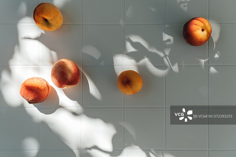 树荫下桌子上新鲜成熟的桃子，夏季花园水果丰收图片素材