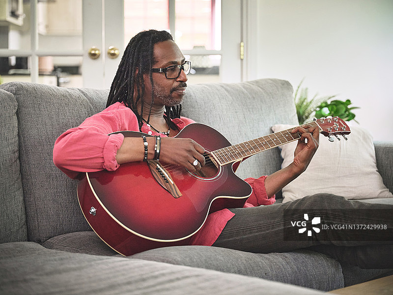 一位老人在家里的沙发上弹吉他图片素材