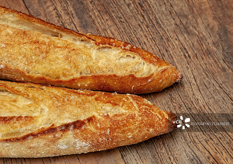 俯视图：乡村木桌上撒有粗盐的两根法棍面包图片素材