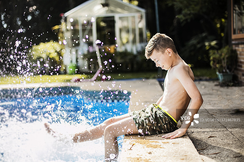 夏天，穿泳衣的男孩在泳池边戏水图片素材