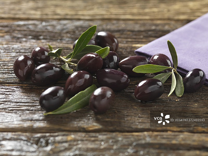 木质表面上的卡拉马塔橄榄与树叶图片素材