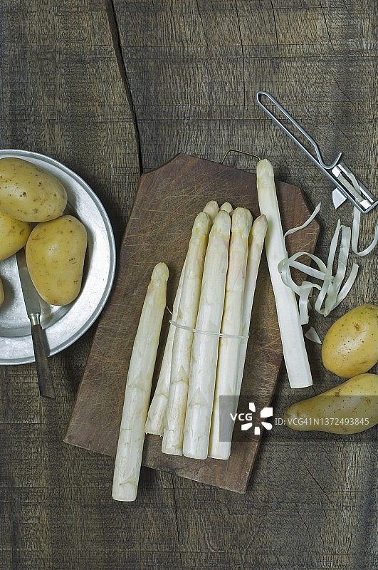 削皮器旁的新鲜白色芦笋和新土豆图片素材