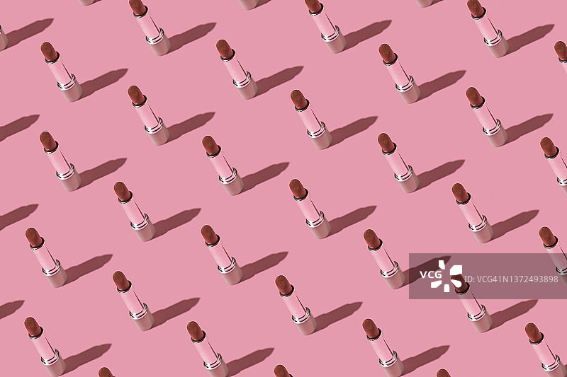 红色口红与银色管身图案，粉色背景，硬阴影。化妆、个人护理和性感概念图片素材