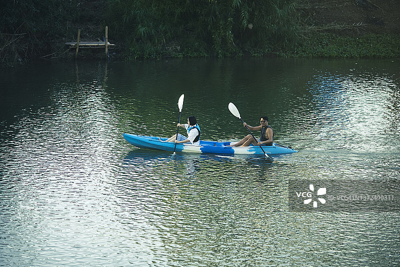 亚洲家庭的兄妹在河上划皮划艇图片素材