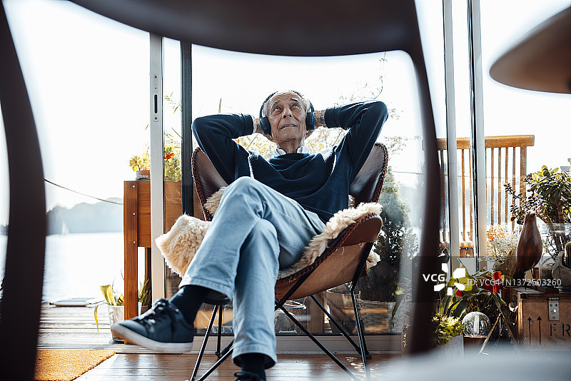 在船屋戴无线耳机听音乐的老年男人图片素材