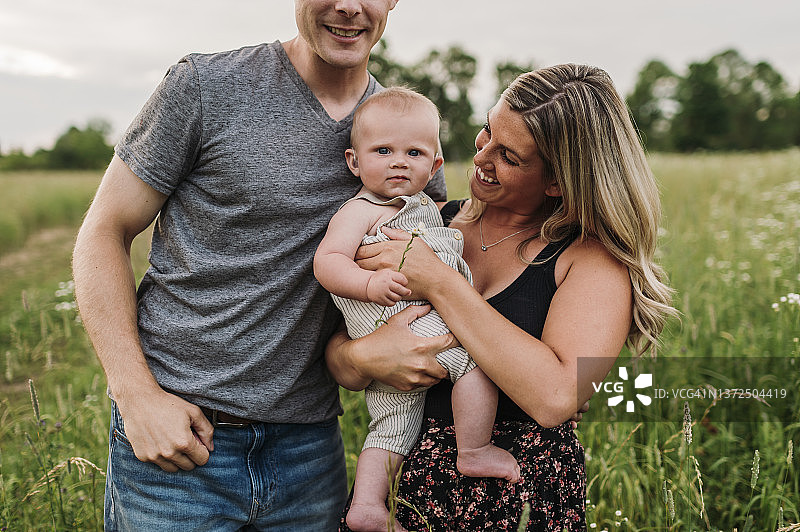 幸福的父母和可爱的男婴站在花园里图片素材