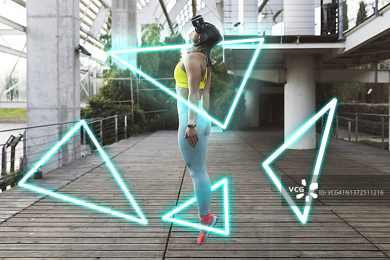 戴着VR眼镜在人行道上跳跃的年轻女运动员图片素材