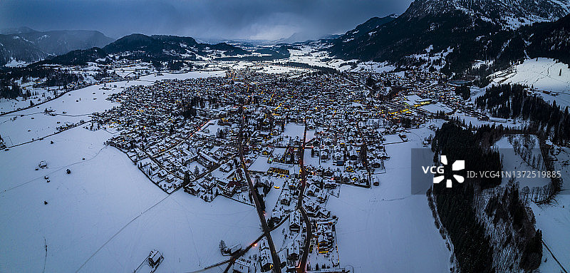 德国巴伐利亚州：阿尔高阿尔卑斯山脉雪镇的黄昏直升机全景图片素材