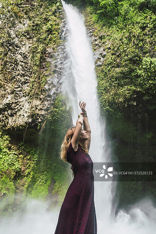 站在哥斯达黎加La Fortuna瀑布前的举手女人图片素材
