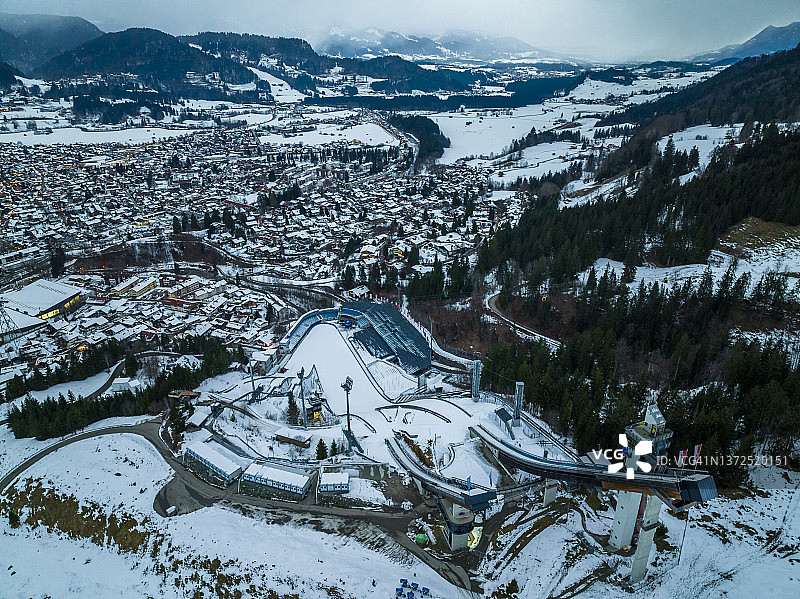 德国巴伐利亚上斯多夫：阿尔高阿尔卑斯山雪镇和滑雪跳台的直升机景观图片素材
