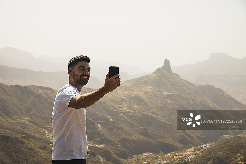 笑容满面的男人在西班牙德戈利亚达·德贝塞拉用手机自拍图片素材