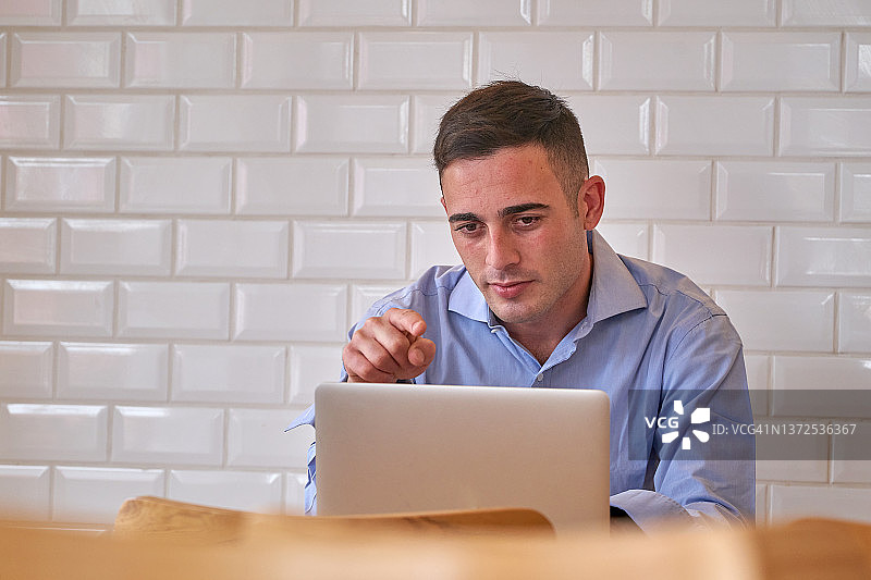 在现代白色砖墙办公室用笔记本电脑工作的男人图片素材