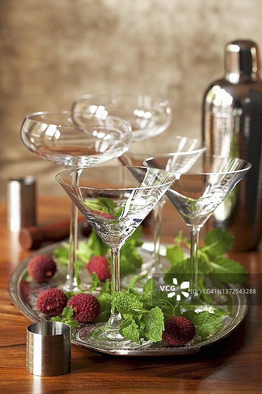 托盘上的空鸡尾酒杯，周围环绕着新鲜薄荷和荔枝图片素材