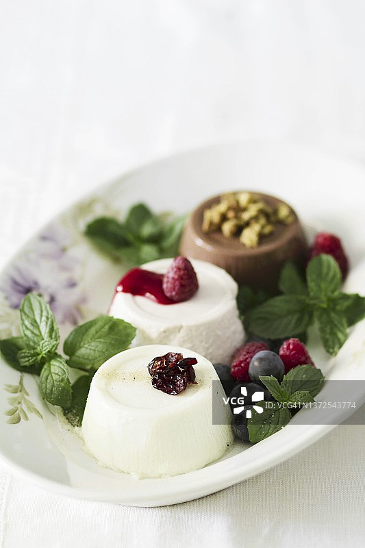 三种不同的意式奶冻，配以浆果和巧克力图片素材
