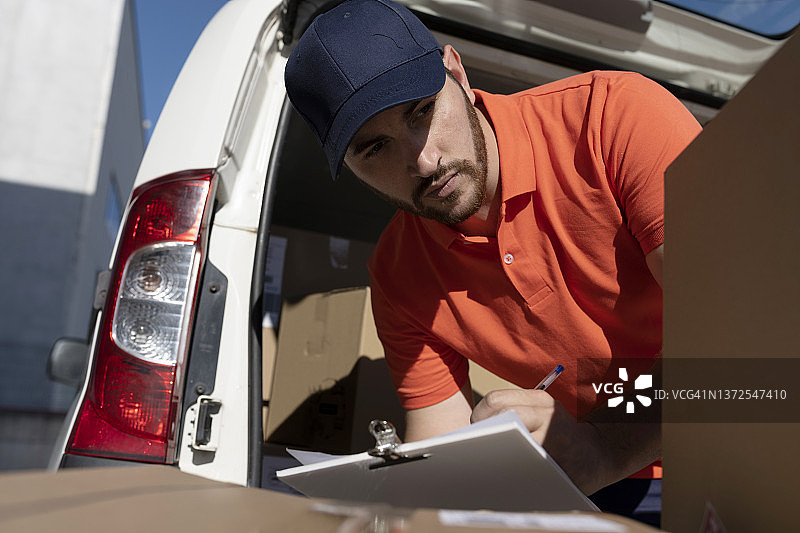 穿着制服的胡子男送货员在检查清单图片素材
