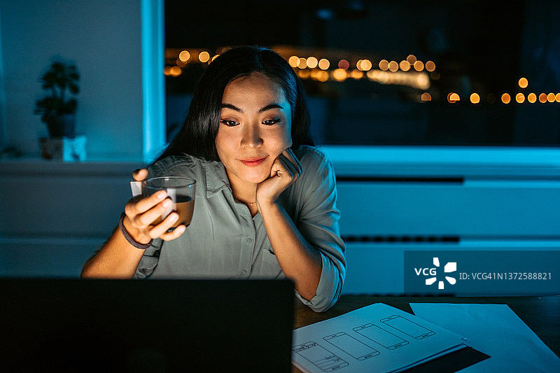 年轻亚洲女性深夜工作时喝咖啡图片素材