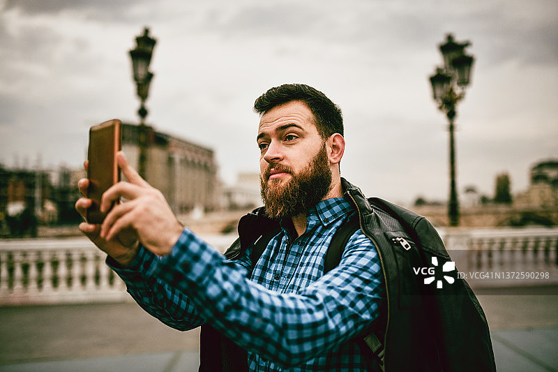 英俊的胡须男子作为游客拍摄城市地标图片素材