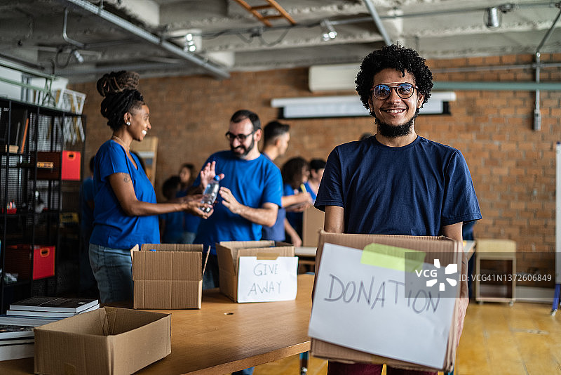 年轻男子在社区中心拿着慈善箱的肖像图片素材