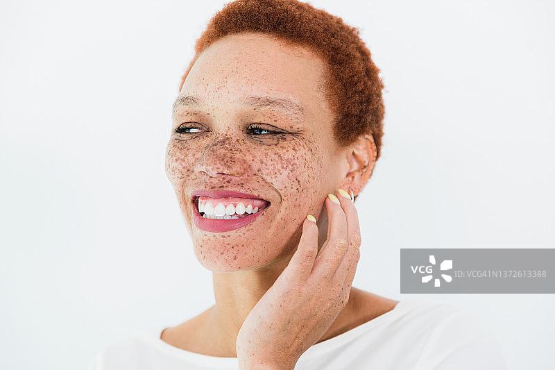 女人手扶脸庞，面带微笑，看向远方图片素材