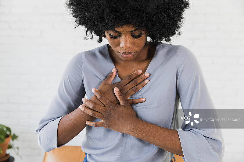 年轻女人手捂胸口，表示疼痛图片素材