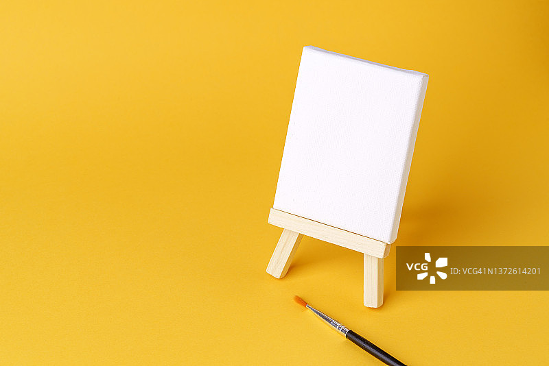 黄色背景上的空白画布画架图片素材