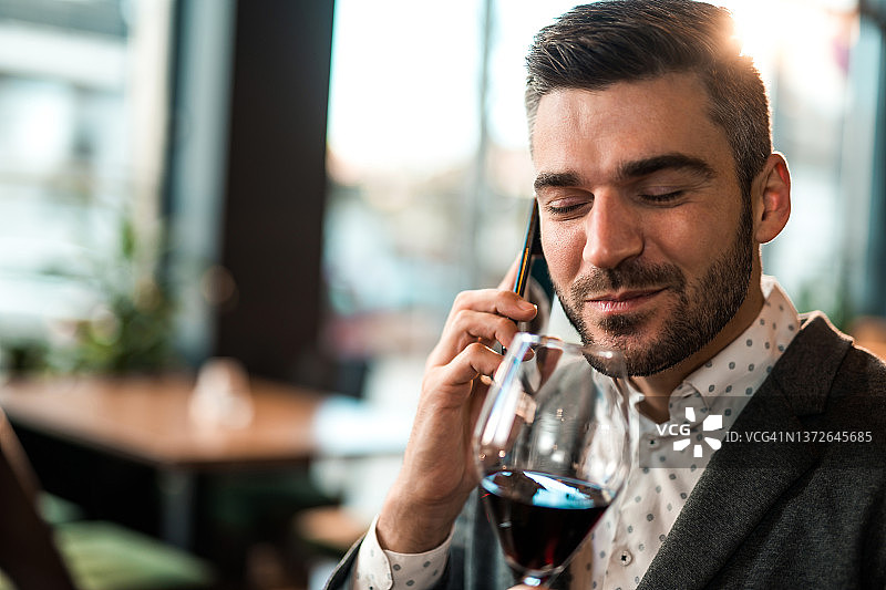 优雅的男人在餐厅享用午餐并打电话时喝葡萄酒的特写图片素材