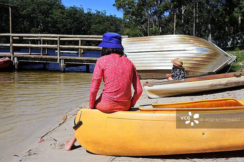 坐在皮划艇上在湖边放松的年轻澳洲姐妹图片素材