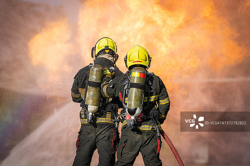 紧急情况下，消防员用水和灭火器灭火图片素材