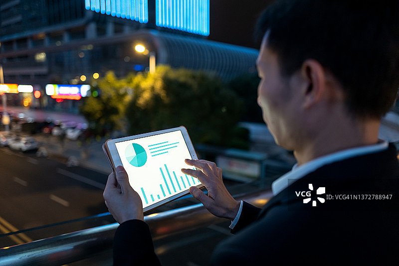 商务男士夜晚使用平板电脑分析数据图片素材