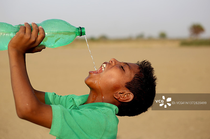 口渴的贫困男孩正在喝水图片素材