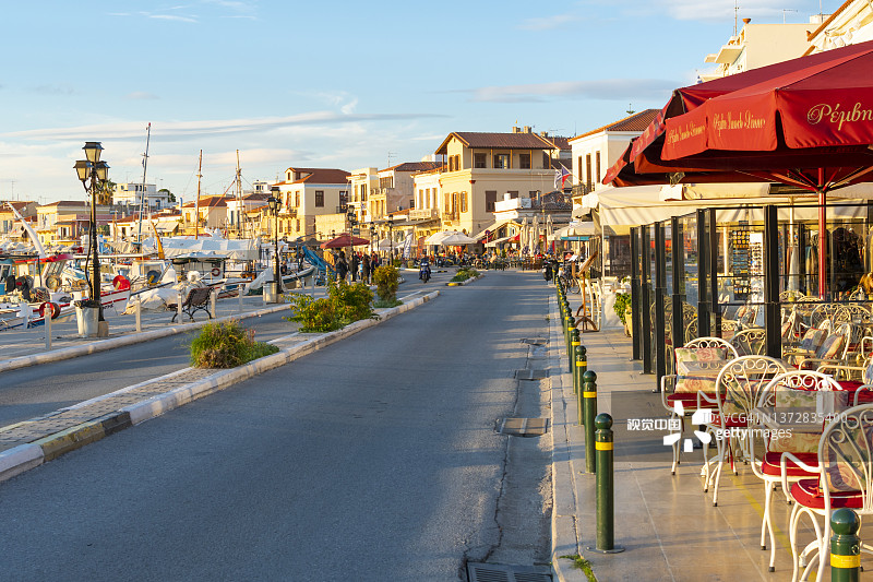 在希腊埃伊纳岛的滨水长廊和主要街道上，商店、咖啡馆和教堂林立，港口码头在日落时分停满了船只。图片素材