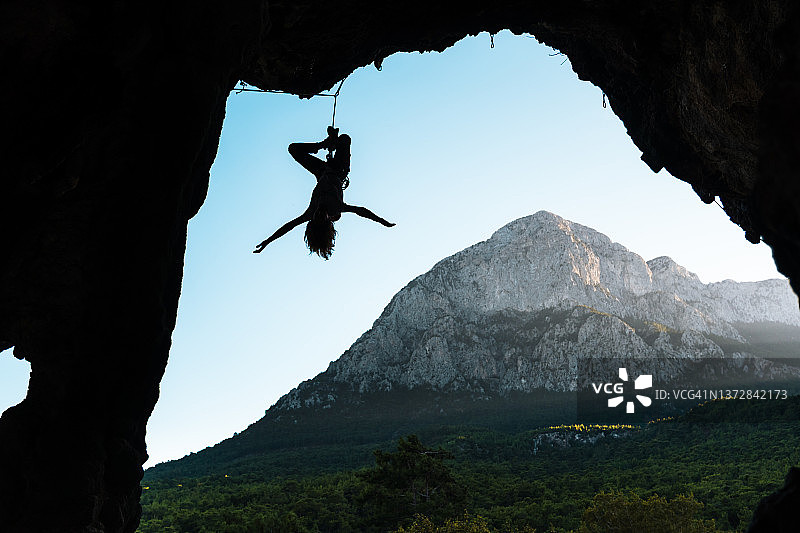 女性攀岩者悬挂在绳索上，洞穴上方视角图片素材