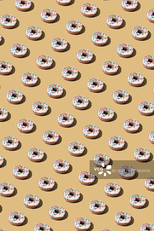 浅橙色背景上的釉面甜甜圈无缝图案图片素材