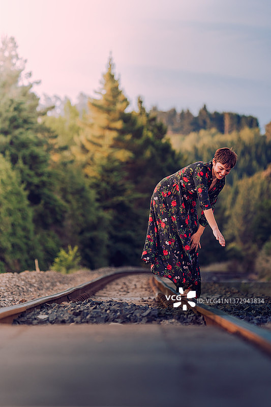 走在火车轨道上的女孩，穿着连衣裙，赤脚感受新西兰的自由图片素材