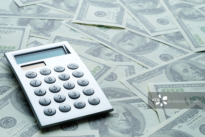 白色背景上的美元和美元纸币，以及用于计算全球危机期间损益的计算器。金融经济概念，薪水、贿赂、信贷资金、投资与商业、贷款与保险图片素材
