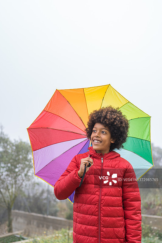 拿着彩虹伞的快乐小男孩图片素材