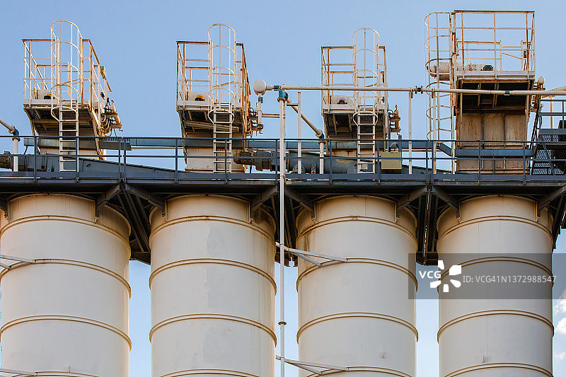 晴朗蓝天下水泥厂的机器：混凝土生产中的物料存储图片素材