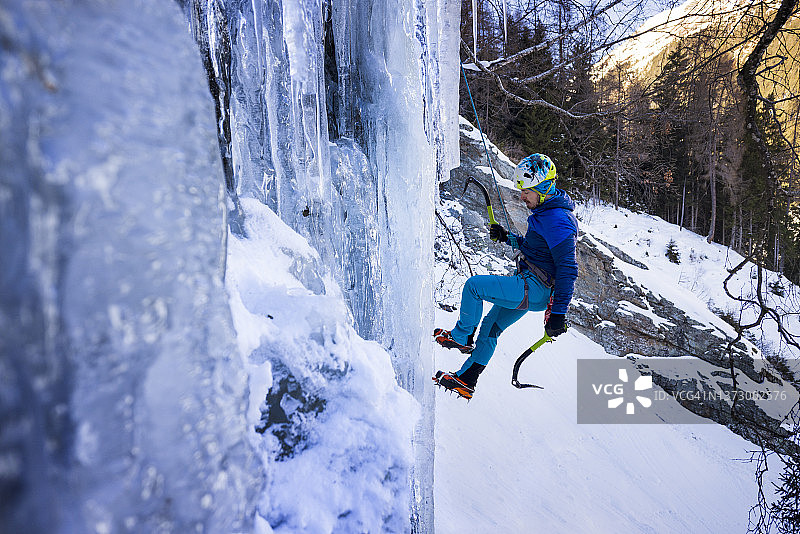 攀冰者从冰冻瀑布上绳降图片素材