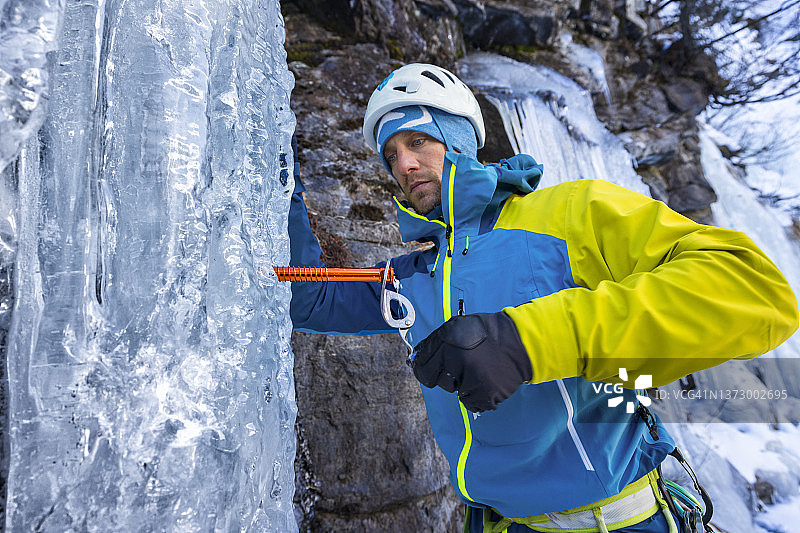 攀冰者在冰冻瀑布中拧入冰锥图片素材